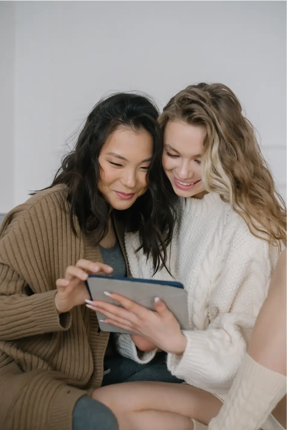 two smiling women working on a digital planner on their i-pad