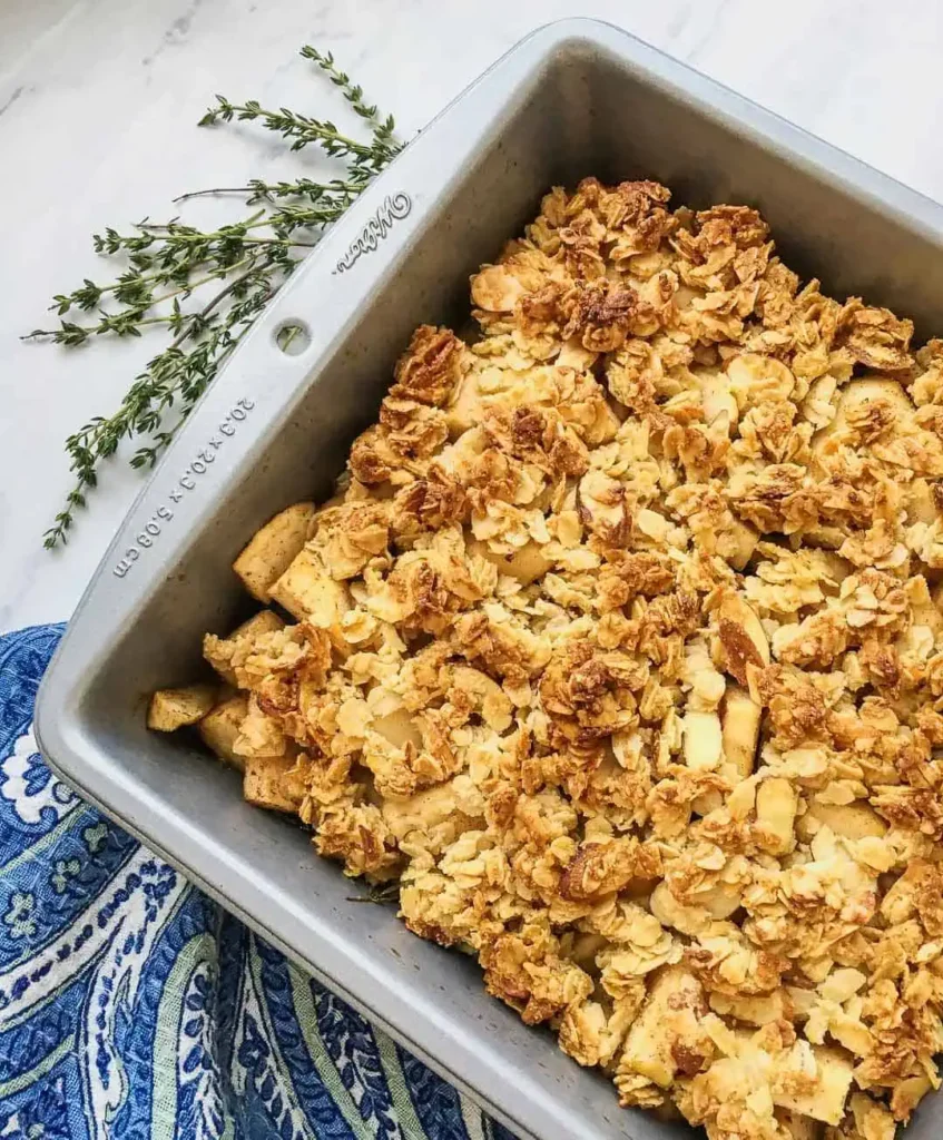 A tray of apple crisp on a table with a pretty blue napkin