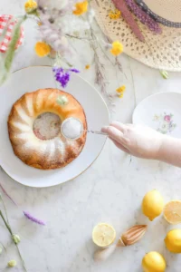 wine cake setting on a table with a lad sprinkling powdered sugar onto it.