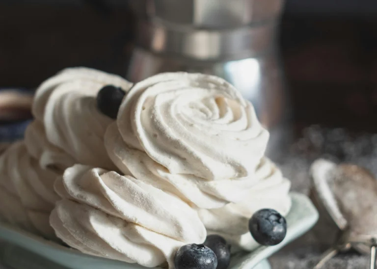 Maple cinnamon whipped cream topping swirled onto a plate, garnished with blueberries.