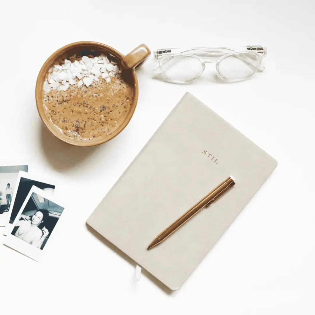 table, journal, coffee cup, reading glasses, blk n wht photos
