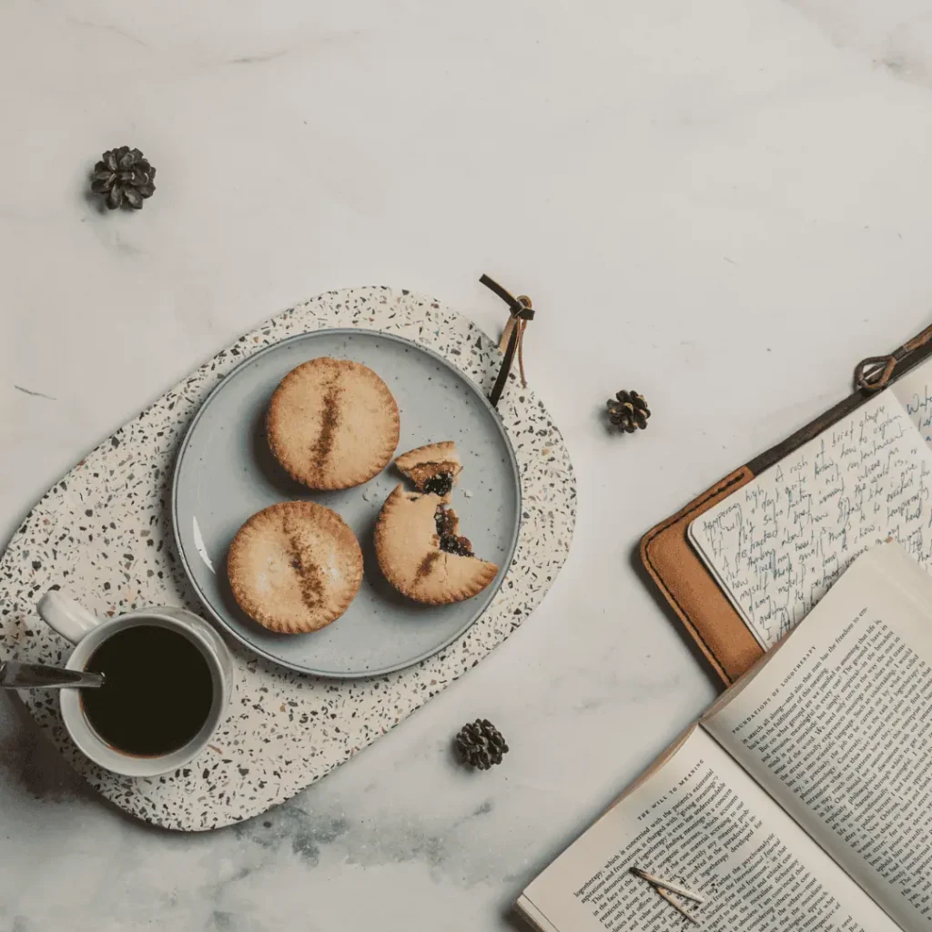 An granite table holding a tray of cookies, cup of coffee and journals for why is journaling so popular.
