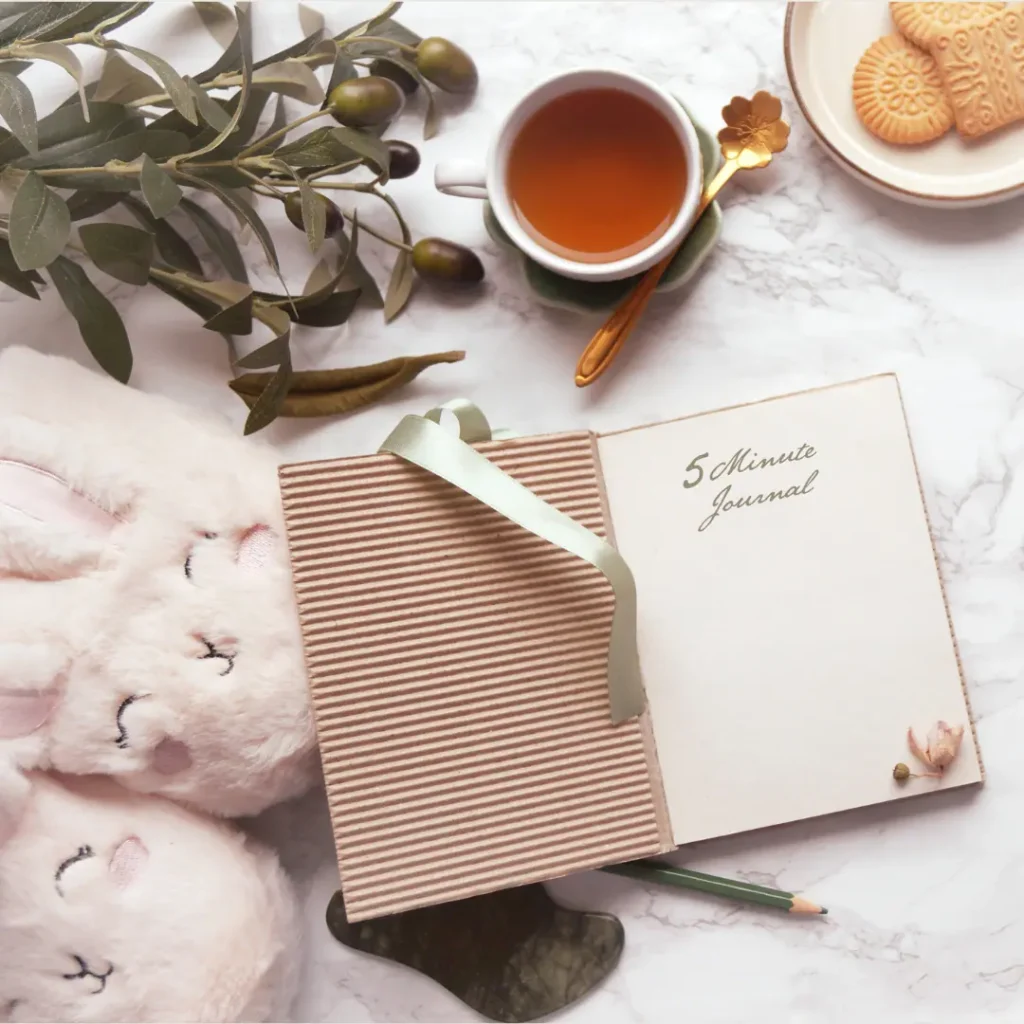 Branches, tea cup, plate of cookies and open journaling book, pencil for why is journaling so popular