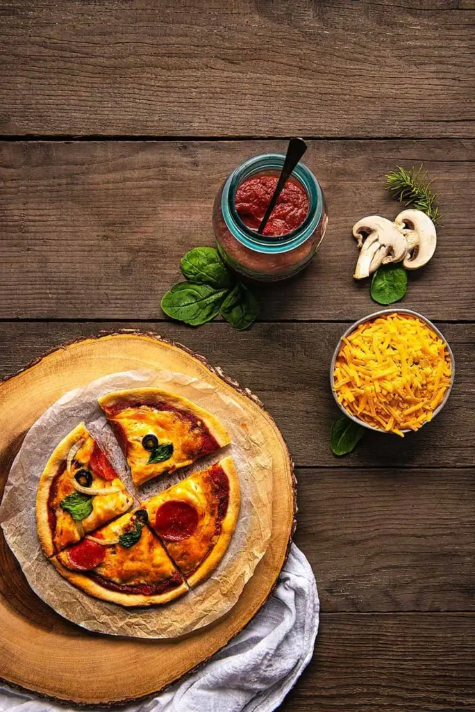 One baked pizzeria style pizza, a mason jar with no cook pizza sauce, and a bowl of grated cheese