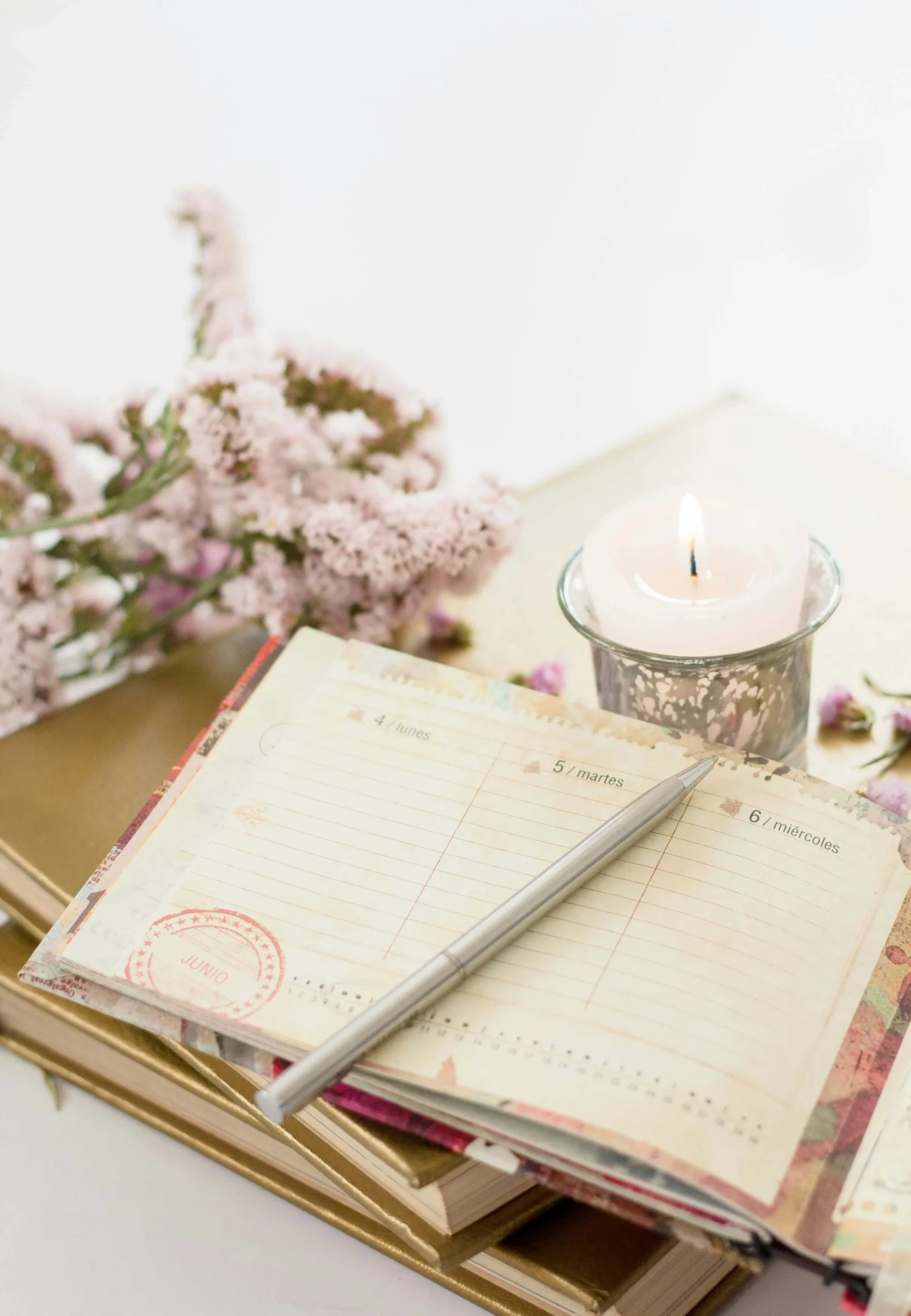 Crafting Your Perfect Writing Space A corner of a desk with journal books stacked, a candle, and flowers