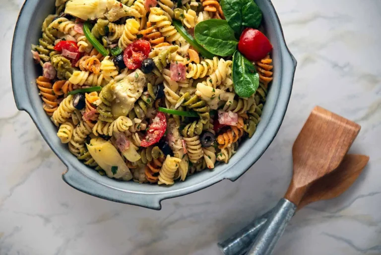 Pasta Salad Easy and Italian. A blue bowl filled with Pasta Salad and in the lower left are two serving spoons.