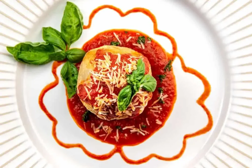 Delectable & Delicious Meatball Wellington An Overhead close-up view of meatball wellington sitting on top of spaghetti sauce and garnished with basil.