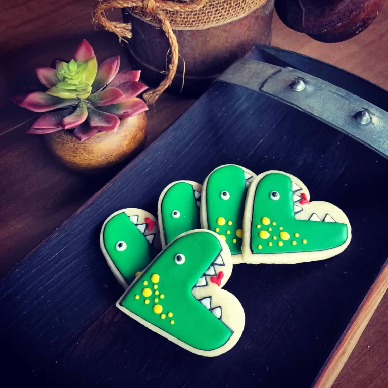 Royal Icing Essentials Every Beginner Should Know. These adorable heart shaped sugar cookies are decorated to resemble t-rex dinosaurs. The royal icing is green, white, yellow and red.