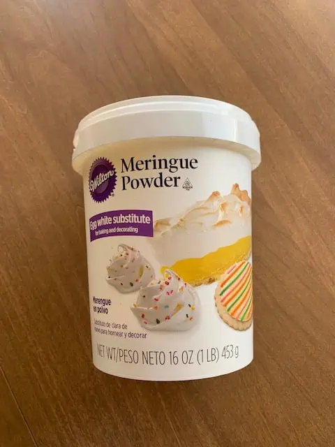 IMG_2557 A 16-ounce container of Meringue Powder, labeled as an egg white substitute for baking and decorating. The label features images of meringue cookies with sprinkles, and a decorated cookie.