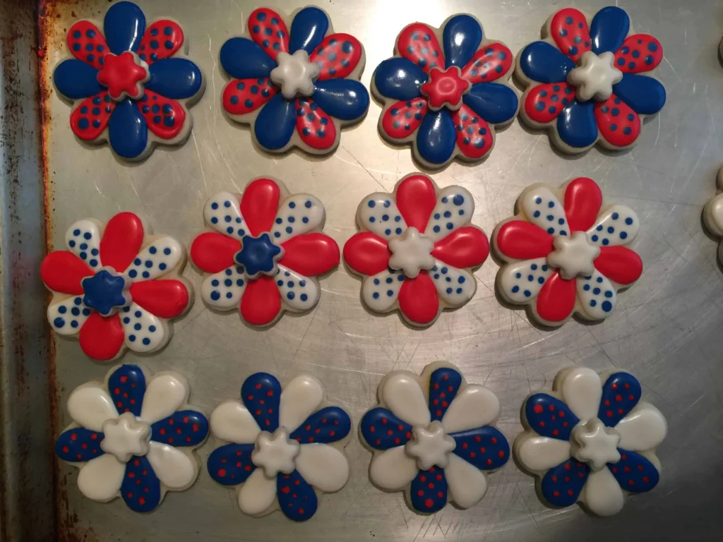 IMG_4268 Flower shaped sugar cookies on a metal cookie tray. Decorated with red, white and blue royal icing.