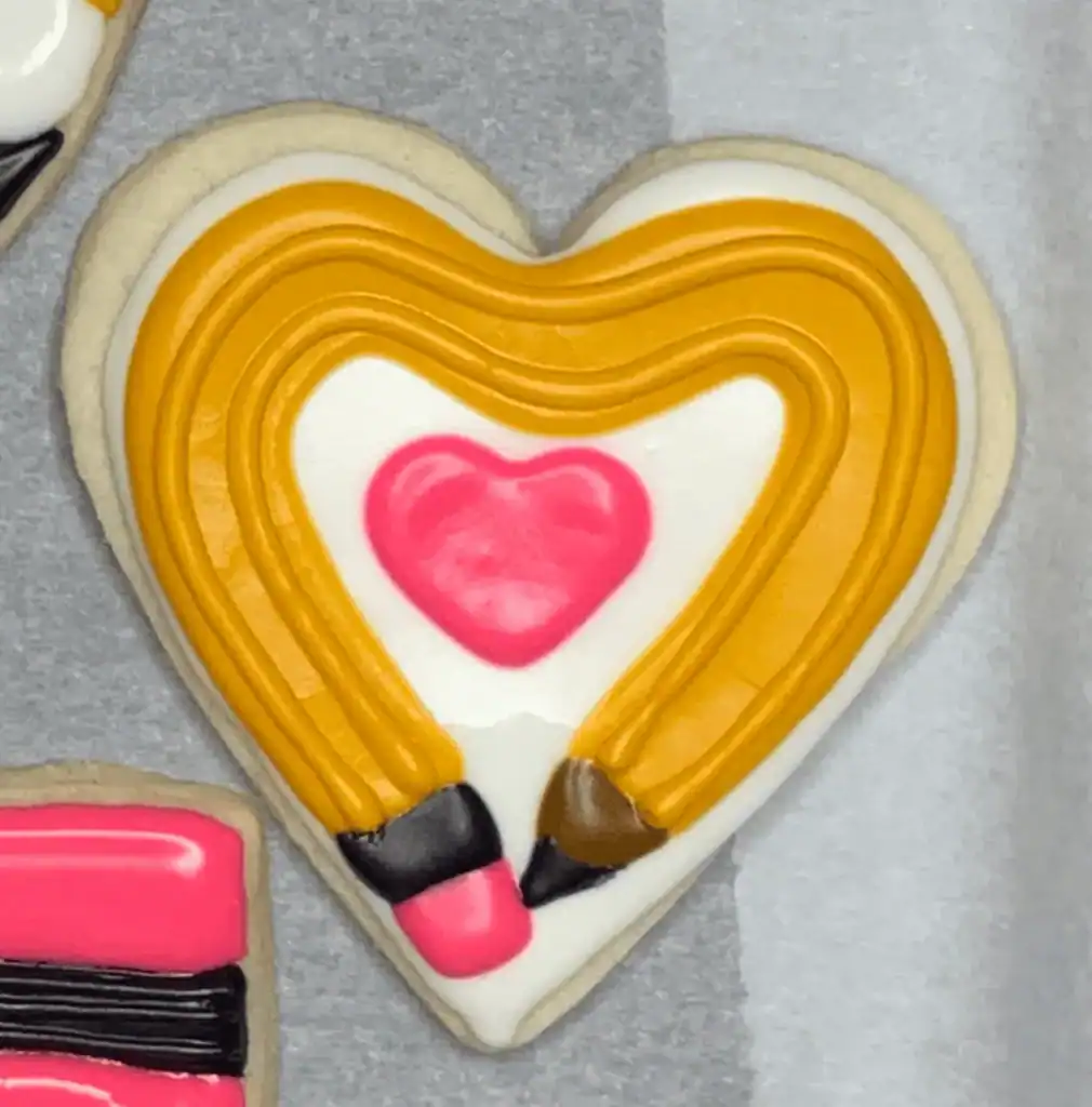 heart shaped sugar cookie with a yellow pencil