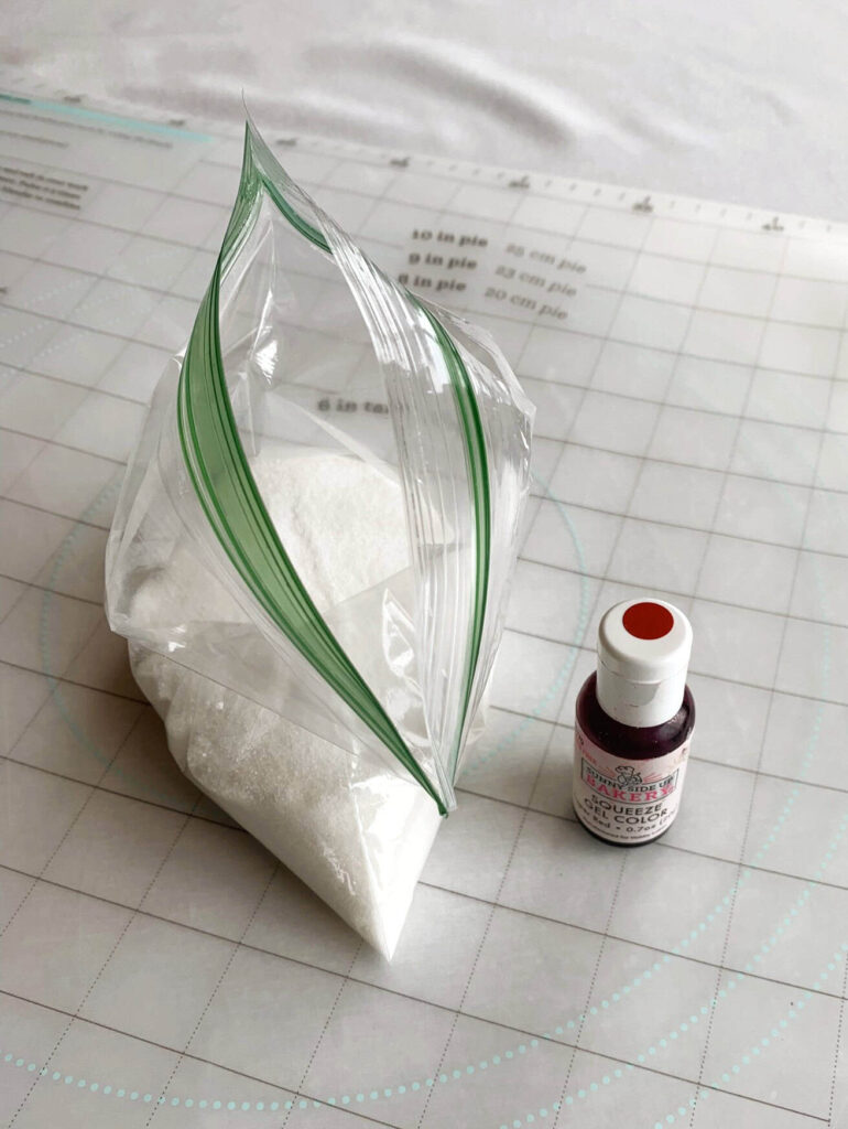 White sugar and small bottle of red food coloring.