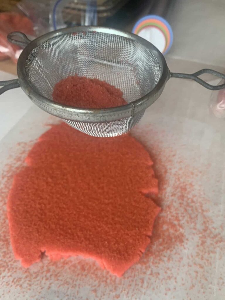 Dusting red sanding sugar onto red sugar cookie dough