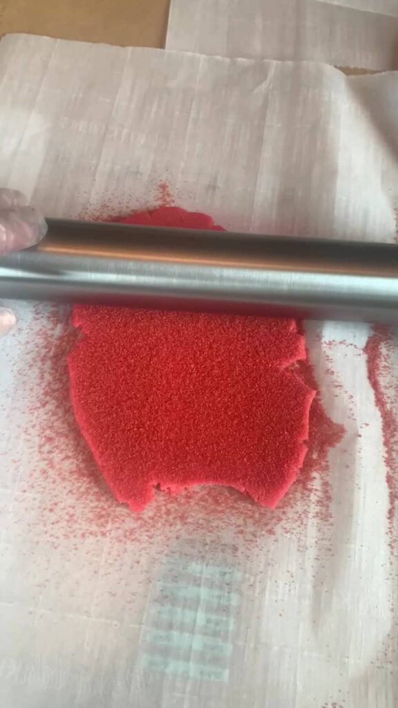 lightly rolling over red sugar cookie dough with sanding sugar.