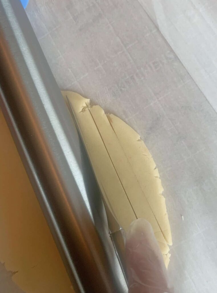 Cutting sugar cookie dough into stripes.