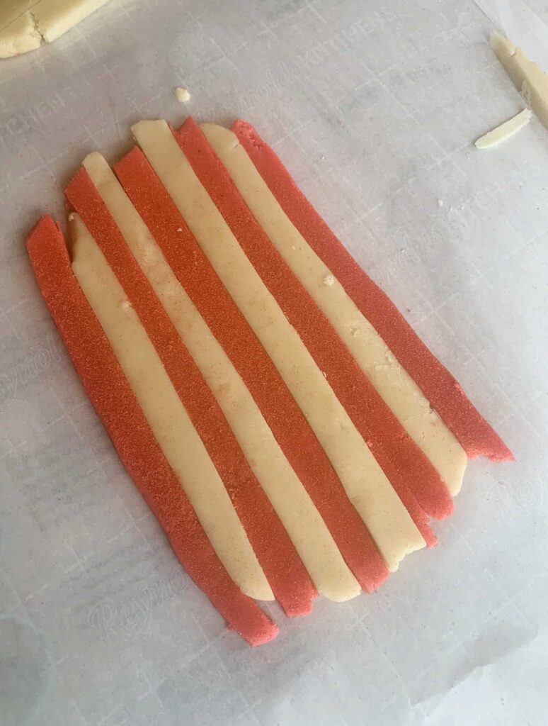 Red and natural colored cookie dough laid out in a alternating stripe pattern.