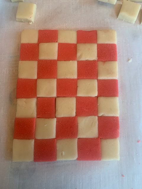 Red and natural colored cookie dough laid out in a checked pattern.