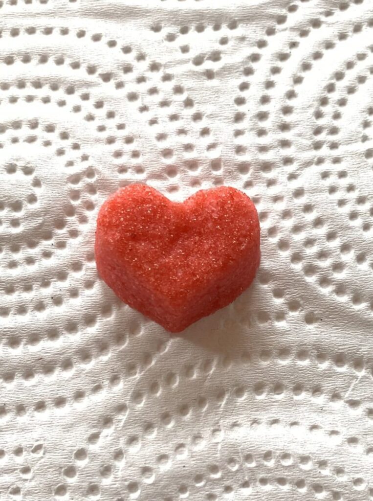 Small heart bite sugar cookie with sanding sugar applied.
