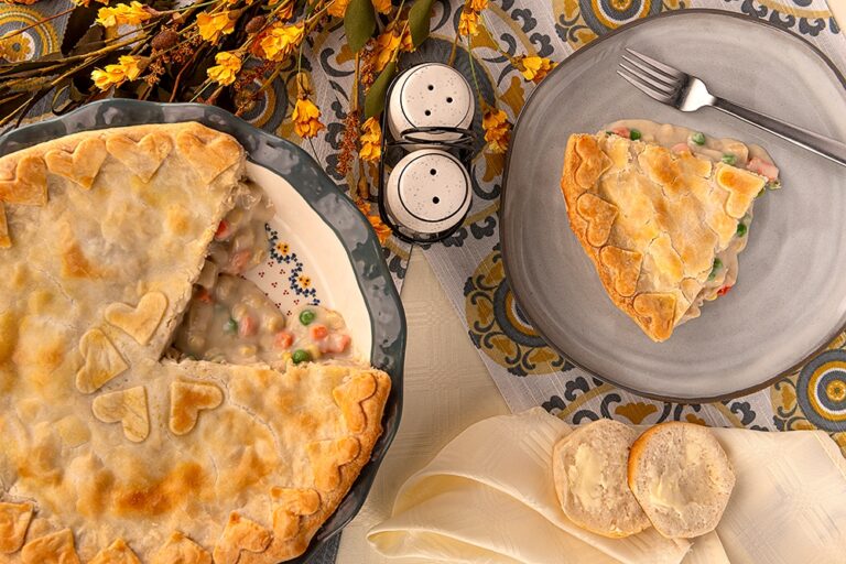 Classic Chicken Pot Pie - A chicken pot pie and a slice sitting on a plate with fork.