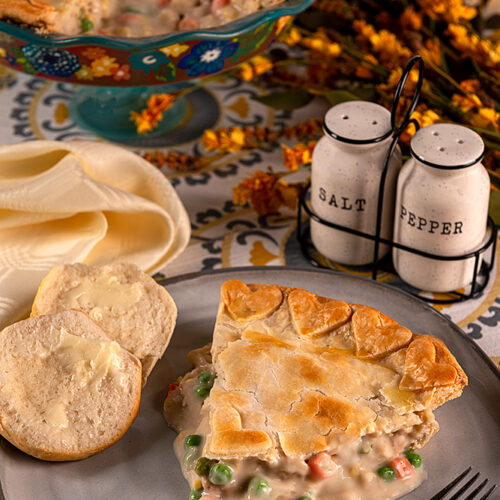 Classic Chicken Pot Pie - A slice of chicken pot pie resting on a plate with biscuits.