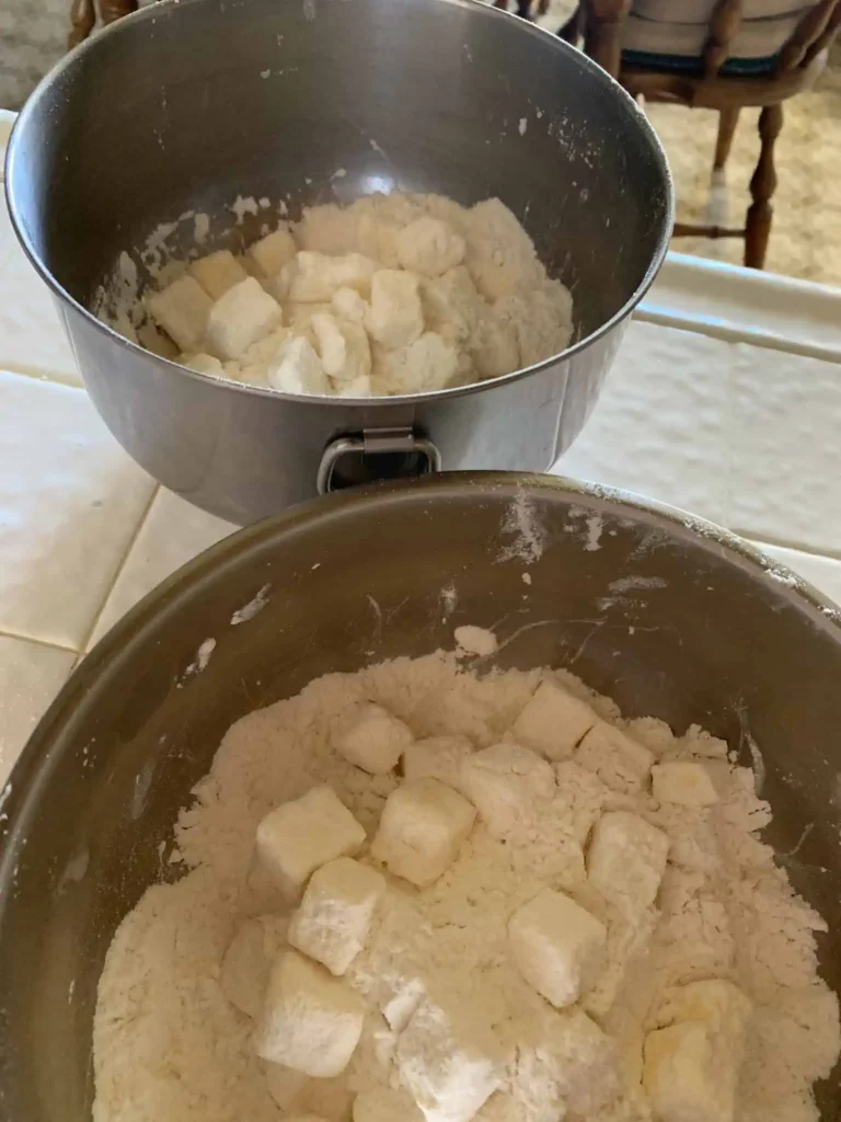 Two mixing bowls with flour and cubed butter used to make flaky pie dough.