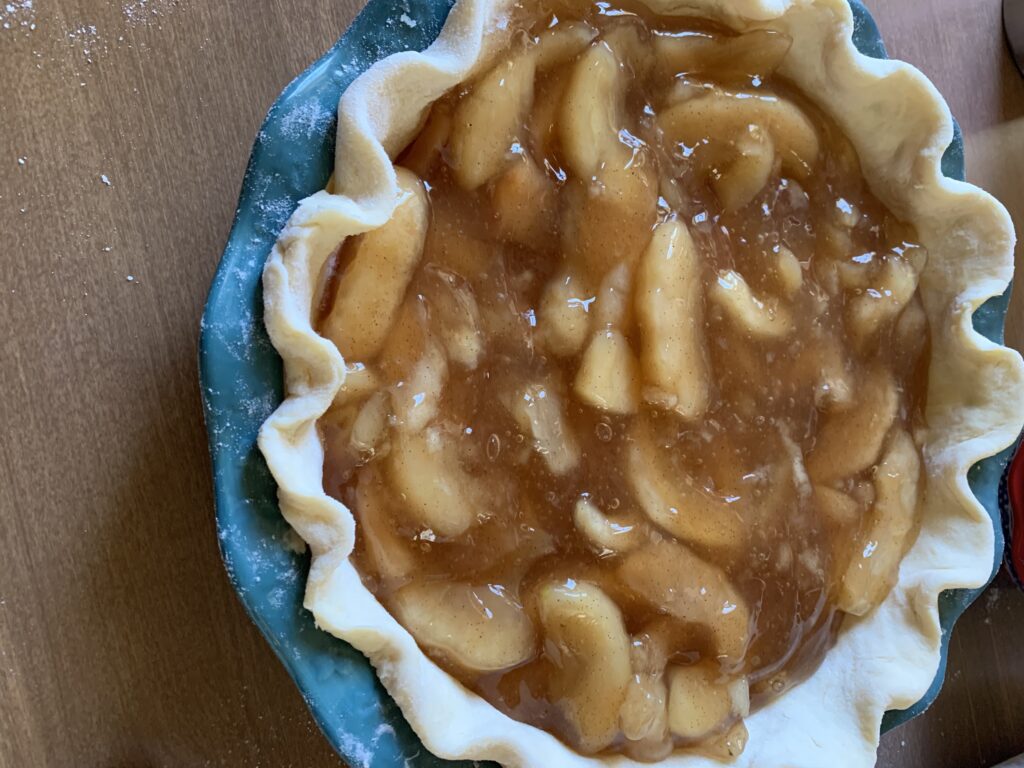 Best Flaky Pie Crust post. pie plate with bottom dough and apple pie filling.