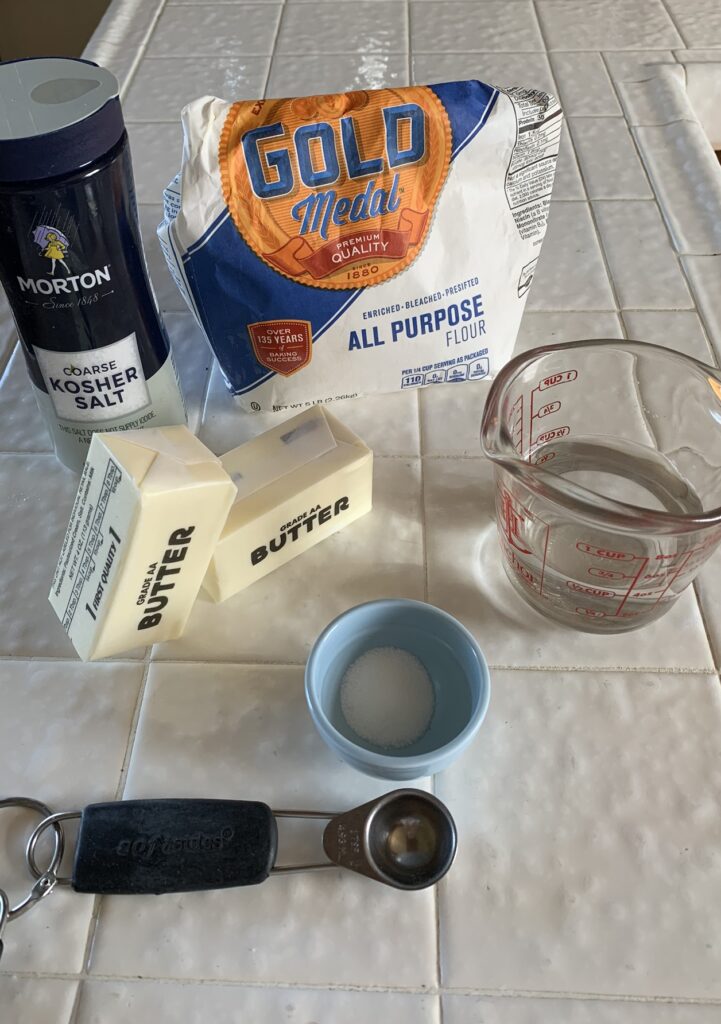 Best Flaky Pie Dough ingredients: Flour, Kosher Salt, Real Butter, water, sugar, and a measuring spoon and cup.